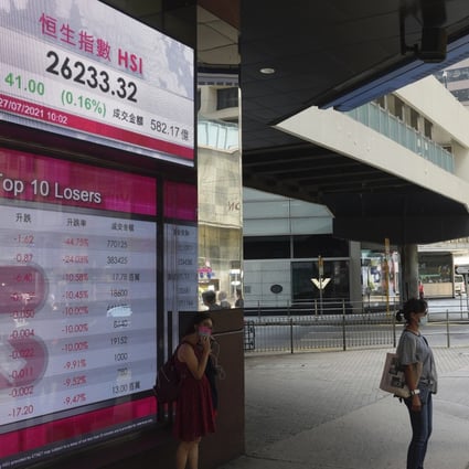 People stand in front of a bank’s electronic board showing the Hong Kong Stock Exchange index. Photo: AP