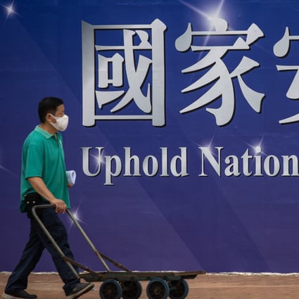 A man pushes a trolley past a banner promoting the national security law in Hong Kong on April 13.  Photo: EPA-EFE