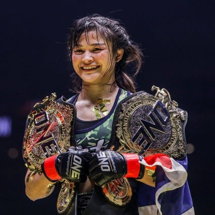 Thailand’s Stamp Fairtex holding the ONE atomweight Muay Thai and kickboxing belts. Photos: ONE Championship.