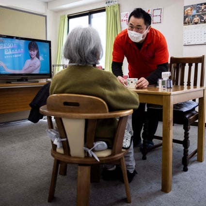 Retired Japanese sumo wrestler Hiromi Yamada, who competed under the name Wakatoba, takes care of an elderly woman at the Hanasaki daycare centre in Tokyo on April 6. Countries around the Asia-Pacific are in dire need of care staff, leading them to think outside the box in addition to importing labour from overseas. Photo: AFP
