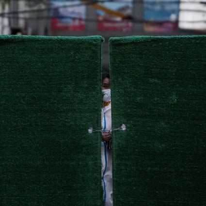 A worker in a protective suit locks a barrier outside of a residential complex in Shanghai, China. Photo: Reuters