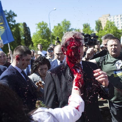 Protesters in Poland throw red paint at Russian ambassador Sergey Andreev as he arrives at a cemetery in Warsaw on May 9 to pay respects to Red Army soldiers who died during World War II. Photo: AP