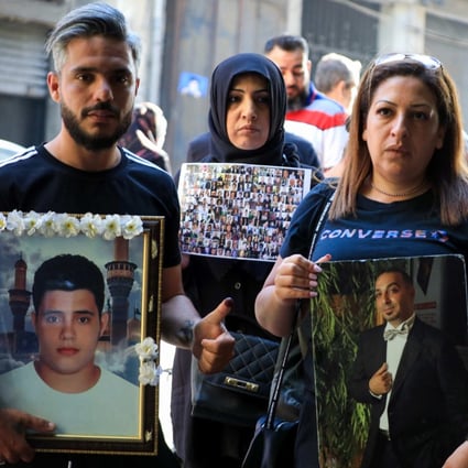 Families of victims of the 2020 Beirut port explosion carry portraits of their relatives outside a polling station in Beirut, Lebanon on May 15. Photo: AFP