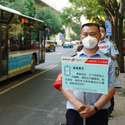 Staff members of Beijing Public Transport hold signboards to remind passengers to show health QR codes at a bus stop in Beijing on May 17, 2022.
Photo: Xinhua
