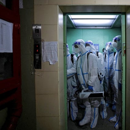 Workers in protective suits take a lift to disinfect a residential area during lockdown, amid the coronavirus  pandemic, in Shanghai on May 18. Photo: Reuters