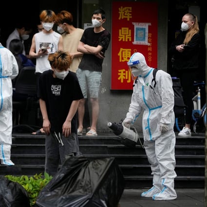 A worker in a protective suit disinfects a person during lockdown in Shanghai on May 20. Photo: Reuters