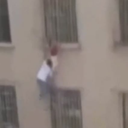Man climbs six floors up the outside of a building to save a girl who became trapped hanging from security bars after falling from a window. Photo: Weibo