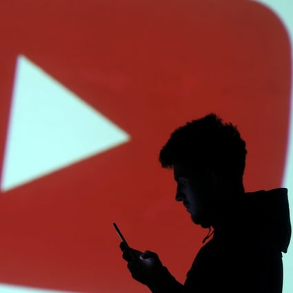 Silhouette of mobile user seen next to a screen projection of YouTube’s logo in this picture illustration taken March 28, 2018.  Photo: Reuters