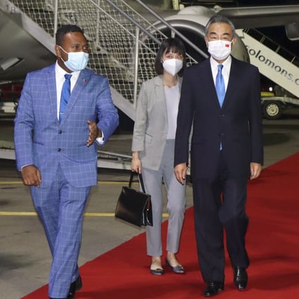 China’s Foreign Minister Wang Yi, center, is escorted from his plane on his arrival in Honiara, Solomon Islands, early on Thursday. His visit comes at the start of an eight-nation tour that comes amid growing concerns about Beijing’s military and financial ambitions in the South Pacific region. Photo: AP