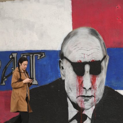 A woman passes by a mural depicting Russian President Vladimir Putin, vandalised with paint, in Belgrade, Serbia, this month. Photo: AP 
