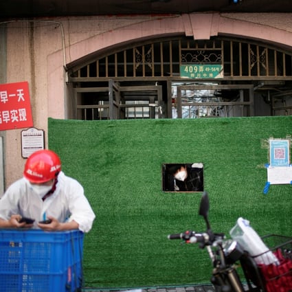 A resident looks out through a gap in the barrier in front of a residential area during lockdown in Shanghai on May 25. Photo: Reuters