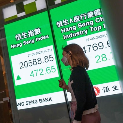 People walk past an electronic display showing the Hang Seng Index in Central, Hong Kong on May 27. Phoyo: AFP
