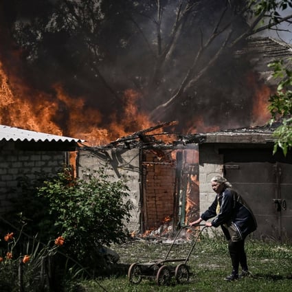 An elderly woman walks away from a burning house garage after shelling in the city of Lysychansk in the eastern Ukrainian region of Donbas. Photo: AFP