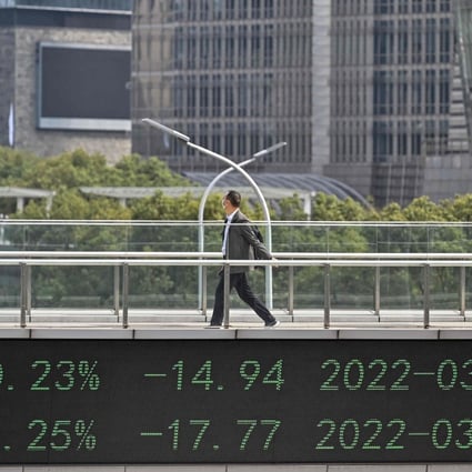 A man crosses a bridge with a stocks indicator board in Shanghai’s financial district on March 16. Photo: AFP