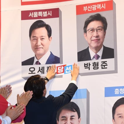 Lee Jun-seok (R), leader of the ruling People Power Party, attaches a sticker saying ‘being elected’ to the photo of incumbent Seoul Mayor Oh Se-hoon during local elections on Wednesday. Photo: EPA-EFE