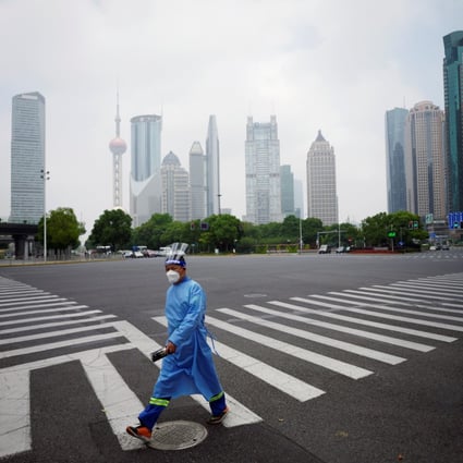 A worker in a protective suit walks on a pedestrian crossing at an intersection in Shanghai’s Lujiazui financial district on June 2, 2022. China’s rigid Covid-19 control measures have been driving reduced carbon emissions since March this year. Photo: Reuters 