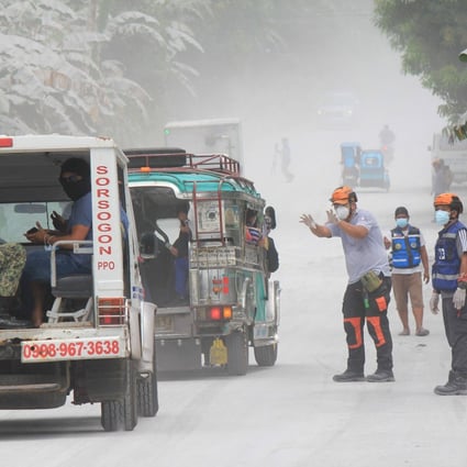 Disaster risk reduction officers guide vehicles on the road at Juban town, Sorsogon Province, after the sudden eruption of Bulusan Volcano. Photo: AFP