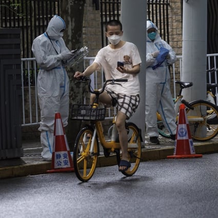 A man rides a bike past workers in protective gear in Shanghai on June 4 as the city deals with new, sporadic community outbreaks of Covid-19. Photo: EPA-EFE