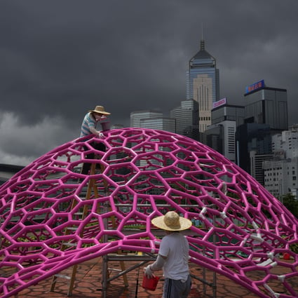 Workers wearing Covid-19 face masks paint a science-themed art installation at a Hong Kong waterfront park on Monday, ahead of celebrations for the 25th anniversary of Hong Kong’s handover to China. Photo: AP
