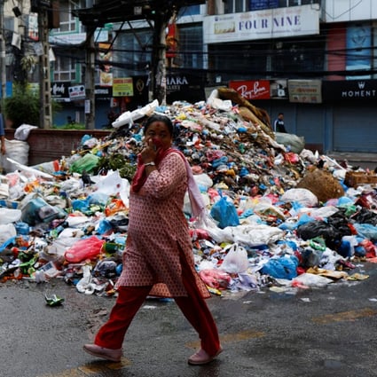 A woman covers her face as she walks past a pile of dumped rubbish   in one of the busiest streets in Nepal’s financial hub. Photo: Reuters
