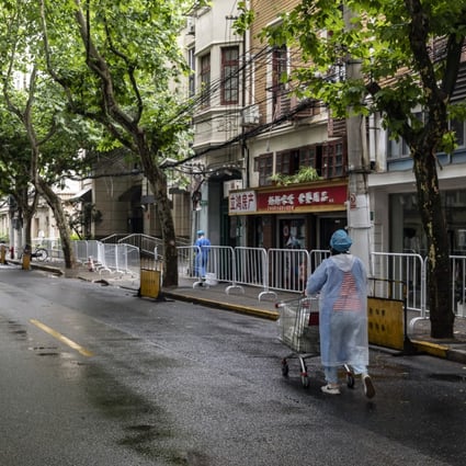 A worker in personal protective equipment pushes a cart of lunch deliveries for residents near a neighborhood placed under lockdown in Shanghai. Photo: Bloomberg