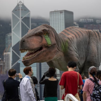 People look at a dinosaur installation against the Hong Kong skyline on June 6. Photo: EPA-EFE
