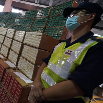 An officer stands next to boxes of illegal cigarettes worth HK$74 million seized by customs officers, during a press conference on May 10. Photo: Felix Wong