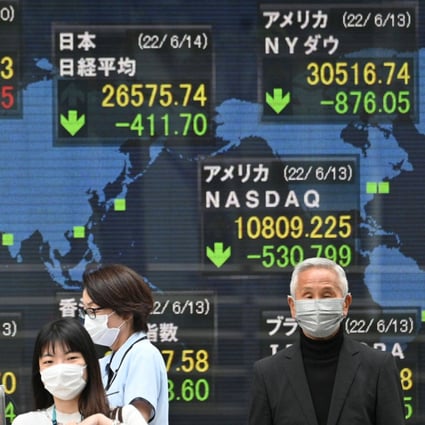 Pedestrians in front of an electronic quotation board displaying the numbers of the world’s stock market in Tokyo on June 14, 2022. Photo: AFP.