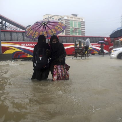 People wade through flood waters in Sylhet, Bangladesh, on Saturday, with millions of homes underwater. Rains are expected to continue over the weekend. Photo: AP 