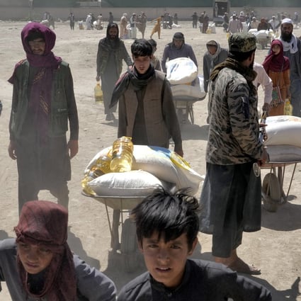 A Taliban fighter stands guard as people receive food rations in Kabul, Afghanistan, on April 30. US sanctions against the Taliban government have exacerbated a food crisis in Afghanistan. Photo: AP