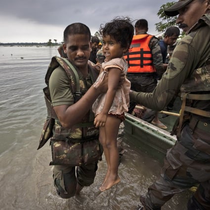 An Indian soldier carries a girl to a safer place after she and her family were rescued from a flooded village in the northeastern state of Assam. Photo: AP