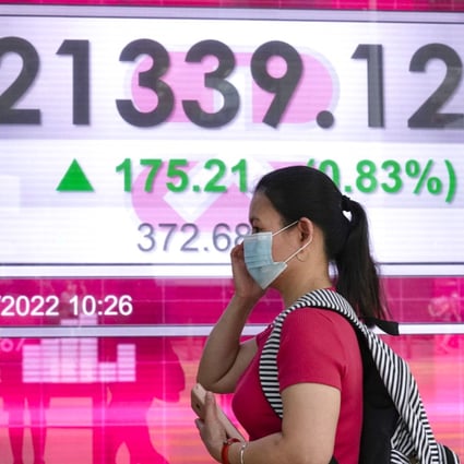 A woman walks past a bank’s electronic board showing the Hong Kong share index in Hong Kong on June 21, 2022. Photo: AP