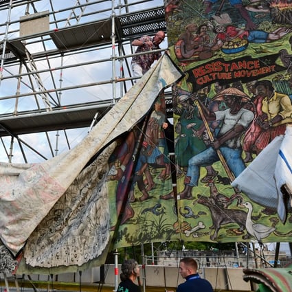 Staff take down the controversial ‘People’s Justice’ banner by the Indonesian artist collective Taring Padi at the Documenta art show in Kassel. Photo: Uwe Zucchi/dpa