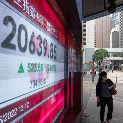 A woman walks past an electronic display showing the Hang Seng Index in the Central district of Hong Kong on May 27. Photo: AFP