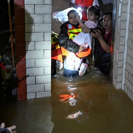 Rescue workers evacuate a child from a flooded building after heavy rainfall in Xinli village of Shaoguan in Guangdong province on Tuesday. Photo: cnsphoto via Reuters