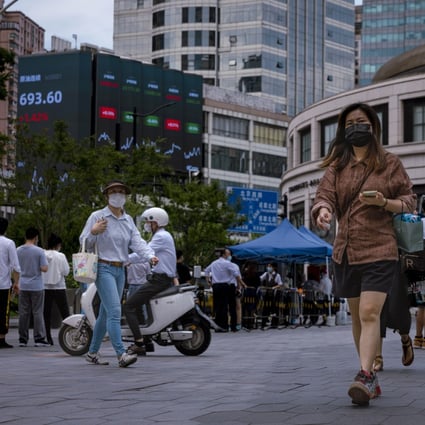 People walk in front of an electronic screen showing the latest economic and stock data in Shanghai on June  23. Photo: EPA-EFE