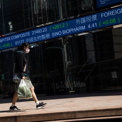 A woman walks past an electronic stock market ticker near the Exchange Square in Cenral, Hong Kong. Photo: EPA-EFE