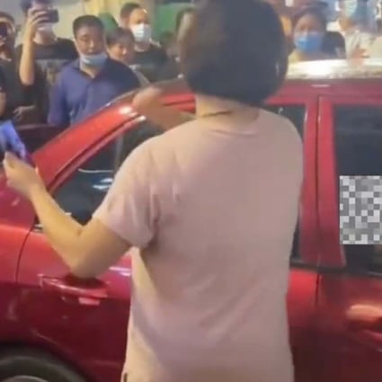 A large crowd cheers for a Chinese woman armed with a brick and her marriage certificate as she confronts her cheating husband and his girlfriend in a car. Photo: Handout