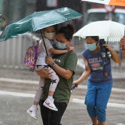 A woman carries a child during heavy showers in Tin Hau on August 19, 2021. Many Hong Kong women are able to join the workforce thanks to the labour of domestic helpers. Photo: Sam Tsang