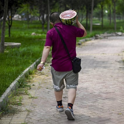 A man carrying a watermelon walks along a path in Beijing on June 21, 2022. Photo: AFP