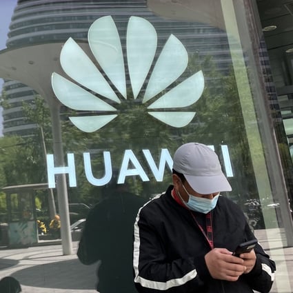 A man reads from his mobile phone in front of Huawei’s logo in Beijing on April 27. Photo: Simon Song
