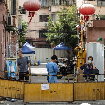 Residents behind barriers surrounding a residential neighborhood placed under lockdown due to Covid-19 in Shanghai on July 6, 2022. Shanghai launched mass testing for Covid in nine districts after detecting cases the past two days. Photo: Bloomberg