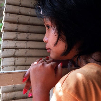 A Cambodian girl rescued from a brothel where she was forced to work hides behind shutters at a house in Phnom Penh. Photo: AFP
