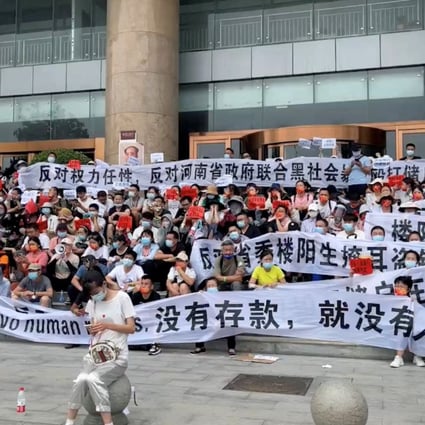 Demonstrators held banners during a protest over the freezing of deposits by rural-based banks, outside the Zhengzhou branch of the People’s Bank of China on July 10, 2022 in the Henan provincial capital, in this screengrab taken from video obtained by Reuters. 