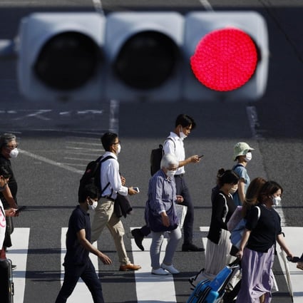 People wear face masks for protection against the coronavirus walk on a pedestrian crossing in Tokyo. Japan set a national record of more than 200,000 coronavirus cases on Saturday. Photo: Kyodo