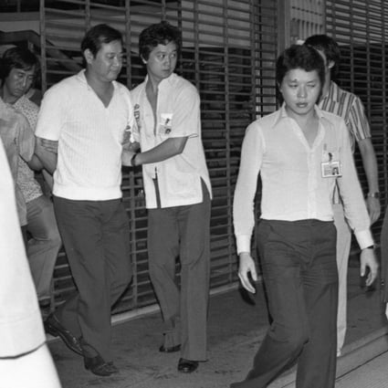 In 1979, a lone gunman in Hong Kong shot a property developer and terrorised four women hostages for five hours before he was talked into surrendering, handcuffed and taken away (above) by police. Photo: SCMP