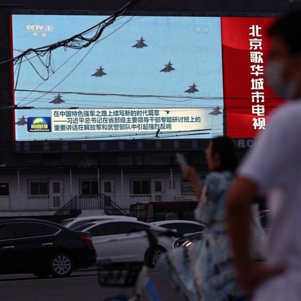 Pedestrians wait at an intersection near a screen showing footage of Chinese People’s Liberation Army (PLA) aircraft during an evening news programme in Beijing on Tuesday. Photo: Reuters