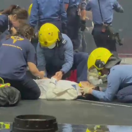 Emergency staff attend to a dancer who suffered a spinal injury when a giant screen fell on him at a Mirror concert in Hong Kong. Spinal injury victims require special handling.