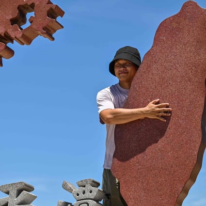A tourist poses with a monument representing mainland China and Taiwan on Pingtan island in Fujian province, on August 6. Photo: AFP