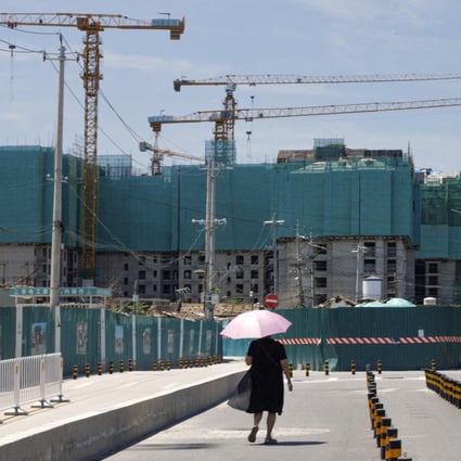 A woman walks near a construction site of apartment buildings in Beijing. Photo: Reuters